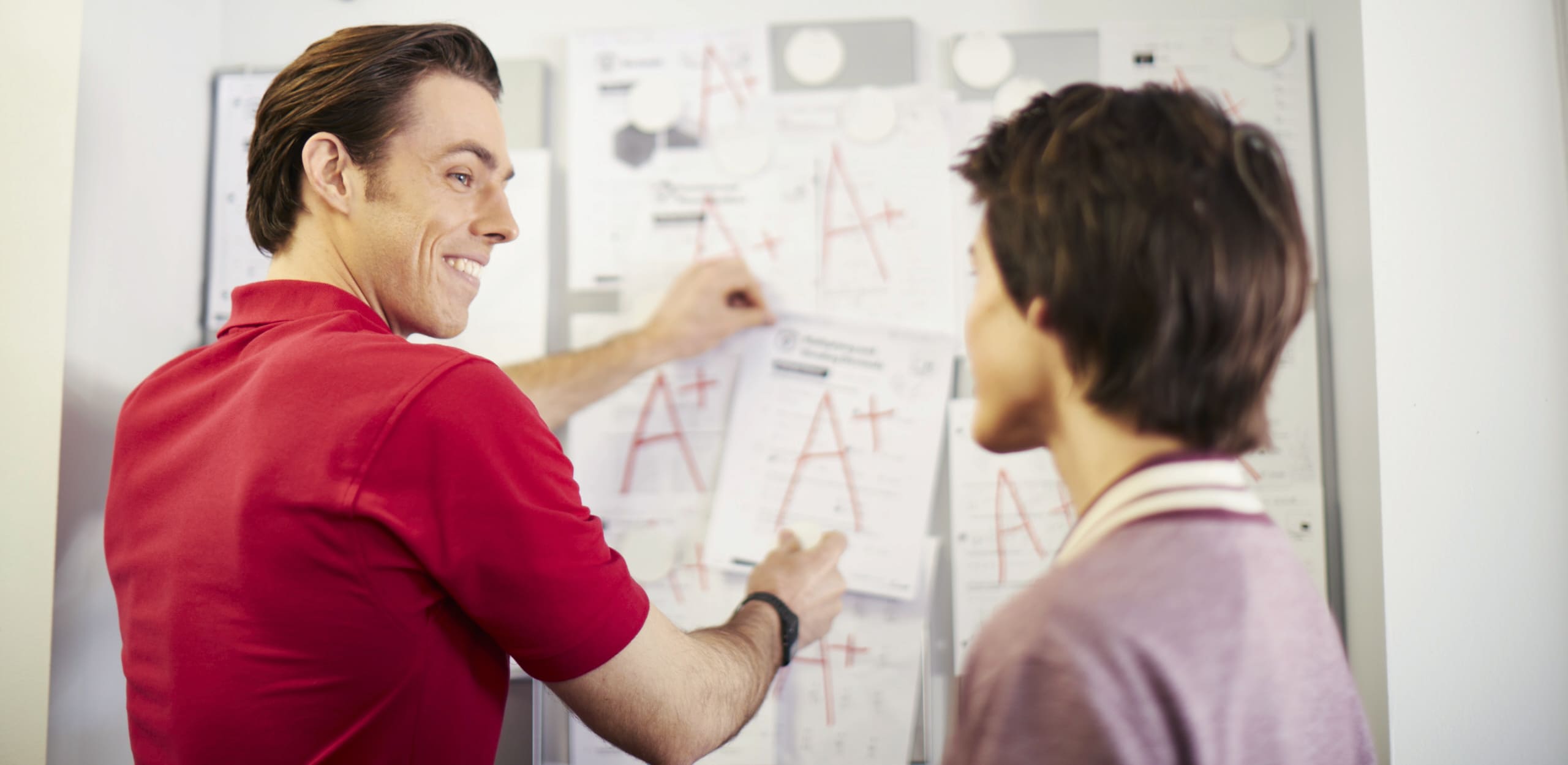 A math tutor putting up good test scores on a whiteboard.