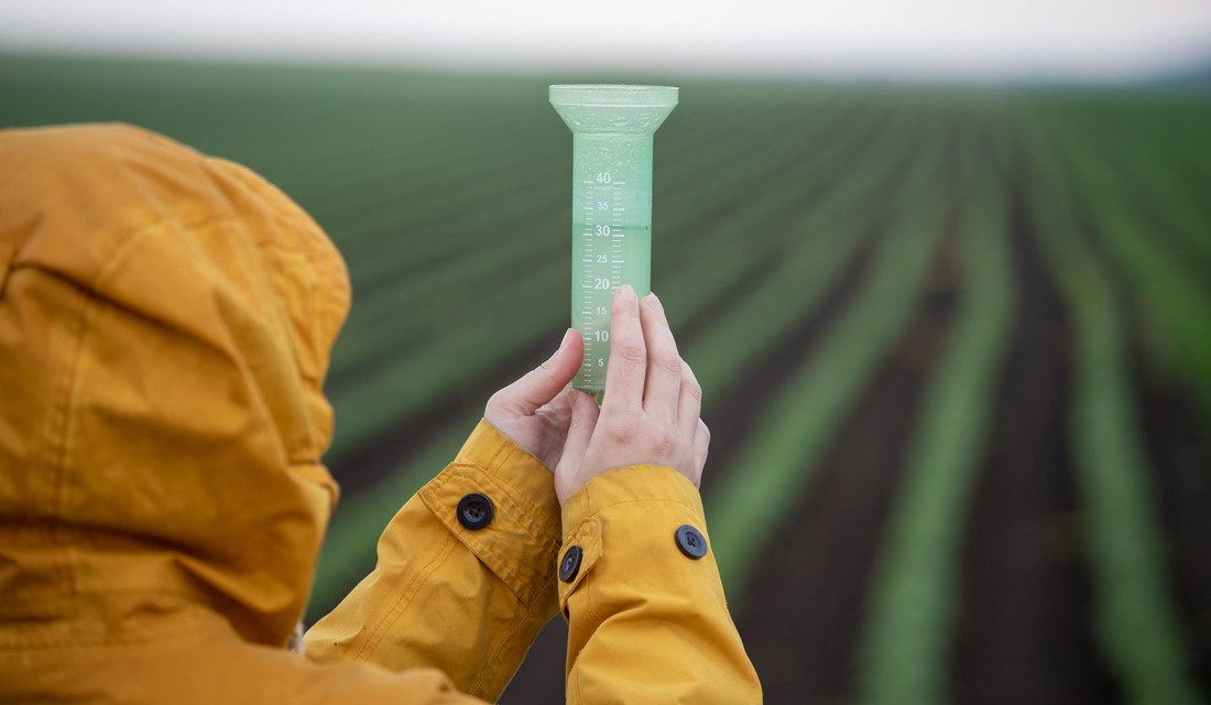 A person measuring rainfall with a rain gauge