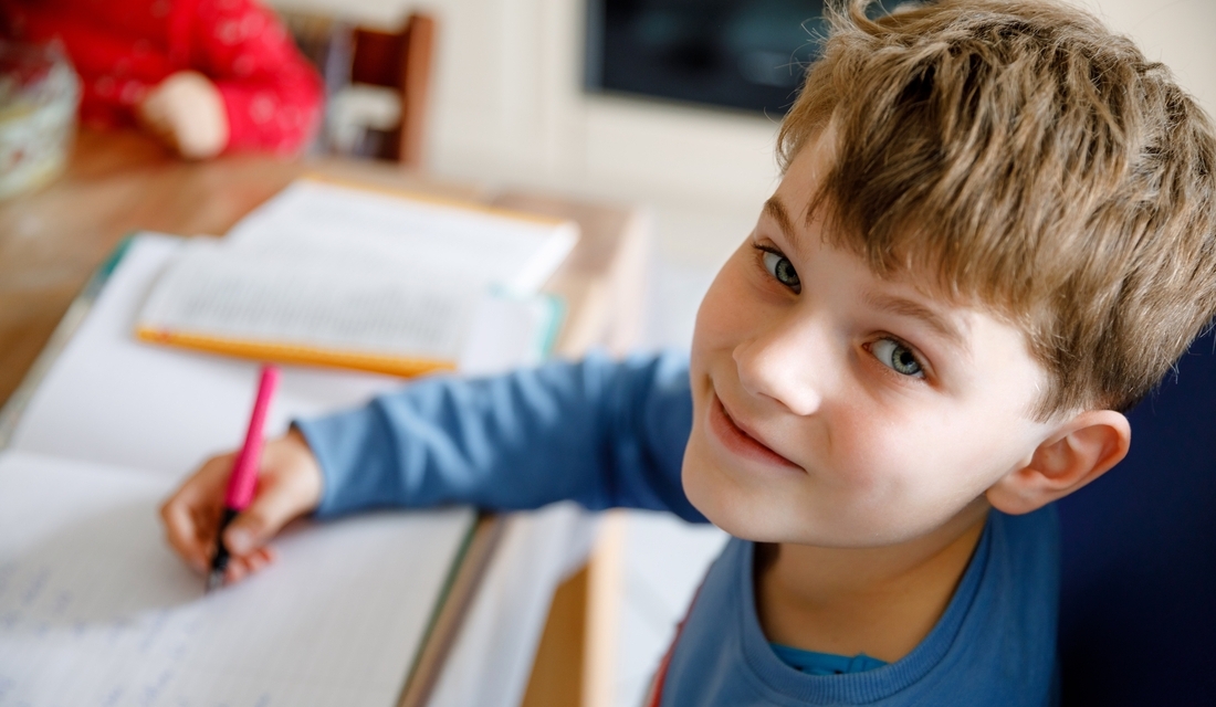Young, cheerful elementary school student working on his math homework
