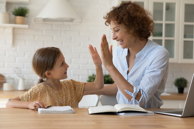 Mother and daughter high five in a kitchen