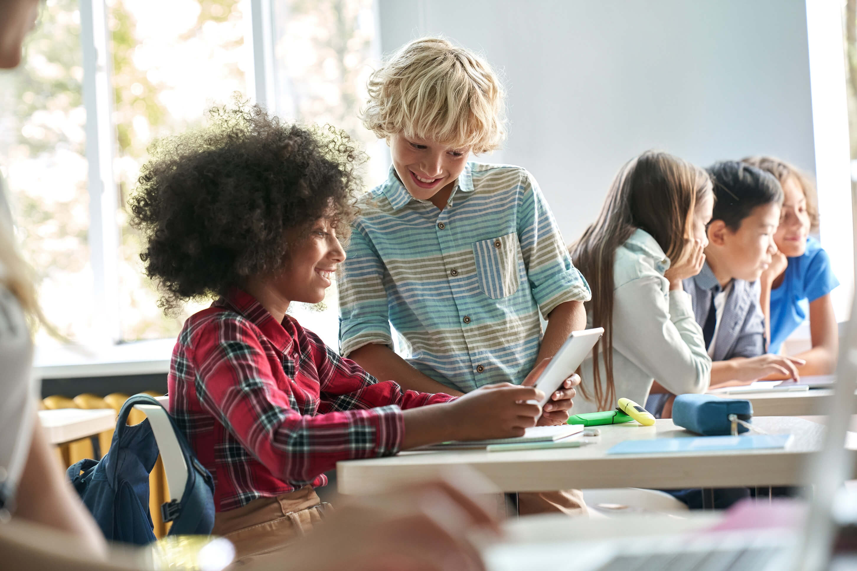 Students in a classroom looking at a tablet.