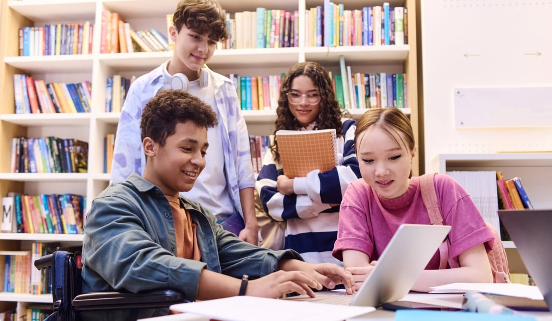A group of students using laptops while studying together in a library setting.
