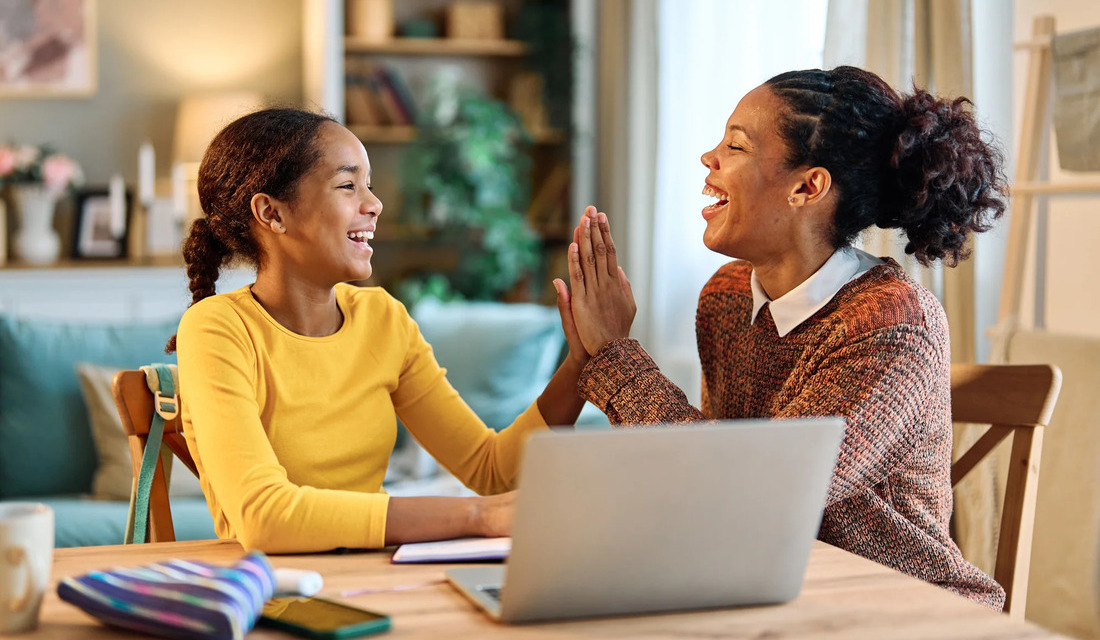 A mother and daughter are seated at a table, their hands intertwined, reflecting a bond of affection and support.