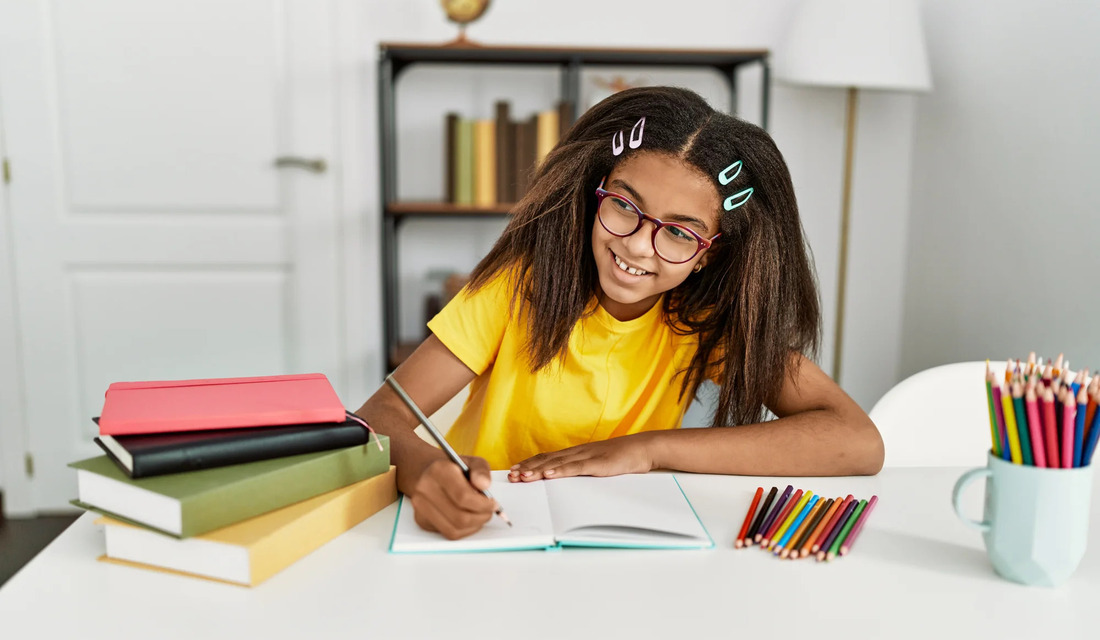 A young girl with glasses diligently writes on a sheet of paper, showcasing her concentration.