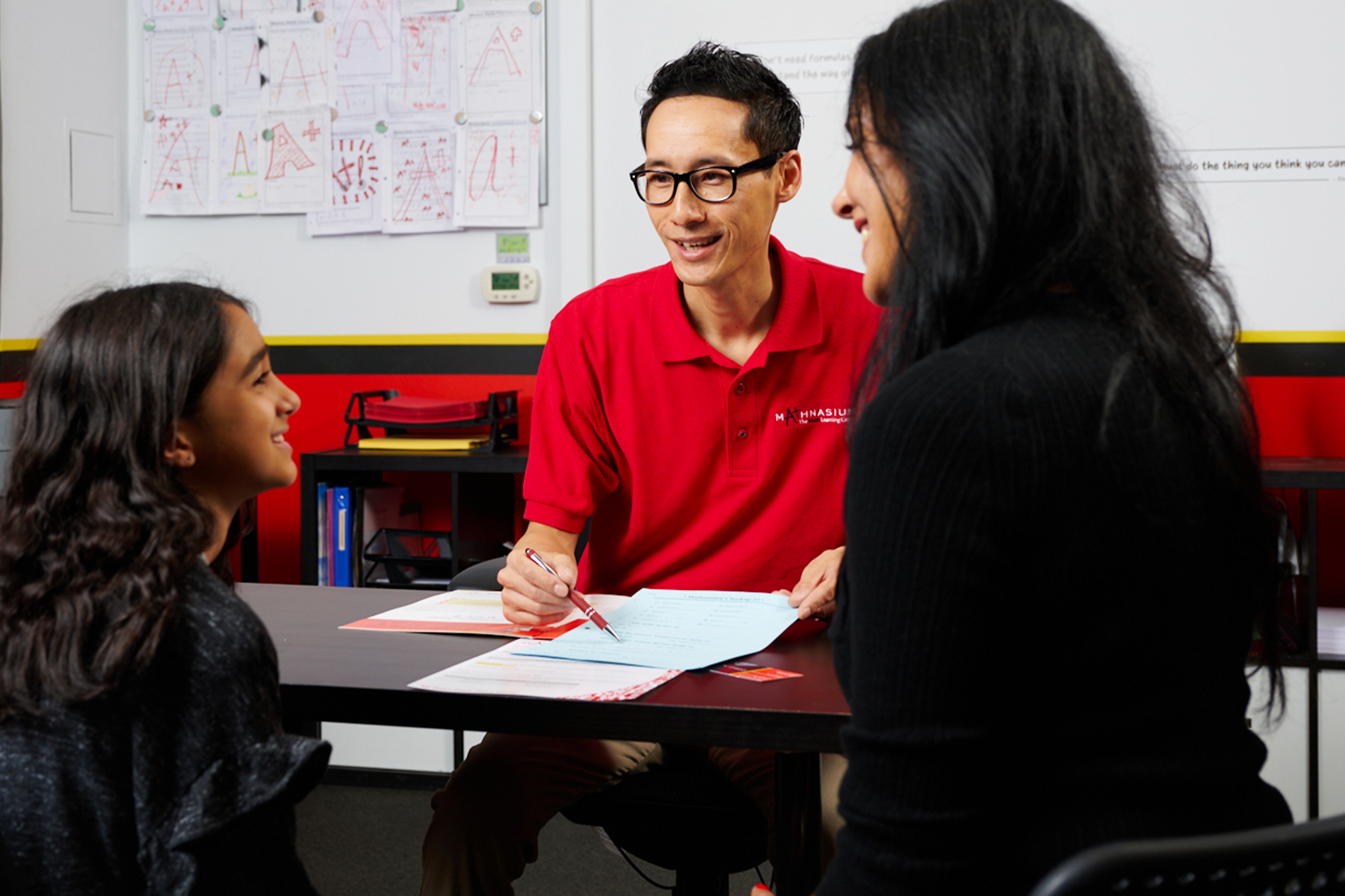 Mathnasium tutor reviewing a student's personalised learning plan with the student and mom.